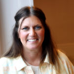 Woman smiling in yellow button up shirt.