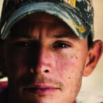Male veteran with camo "Veteran" hat looking into the camera
