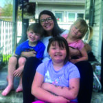 Mother and her children sitting on the steps smiling.